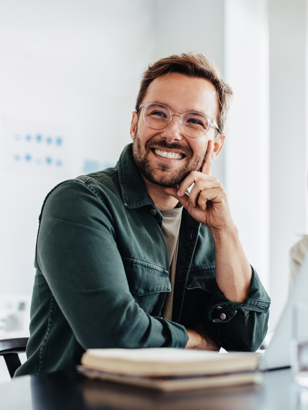 Ein Mann und eine Frau sitzt in einem Besprechungsraum. Er hat ein Notebook vor sich und lächelt.