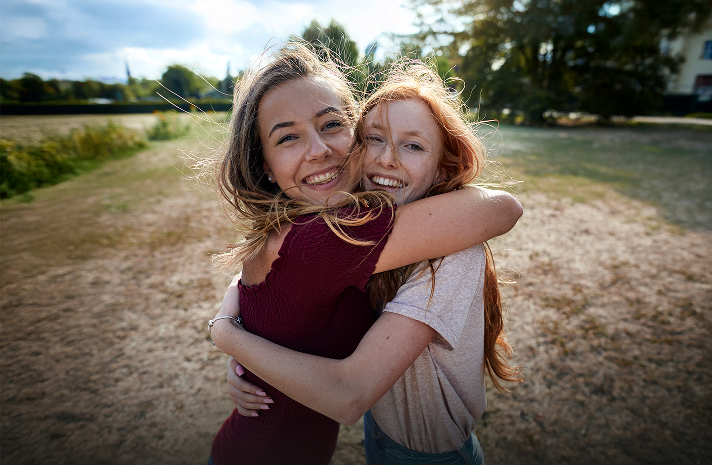 Zwei Frauen stehen in der Natur und umarmen sich